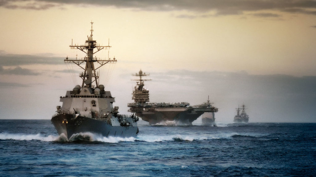 Two Navy Ships sailing into the sunset.