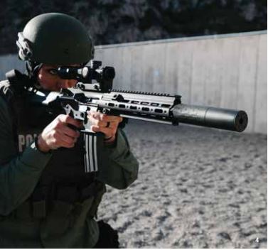 A man aims an automatic rifle with a silencer