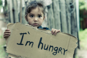 A small child holds a sign saying "I'm Hungry"
