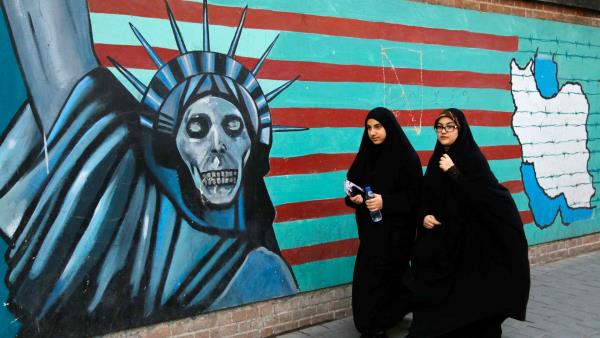 Two women in Iran walk by street art of the Statue of Liberty.