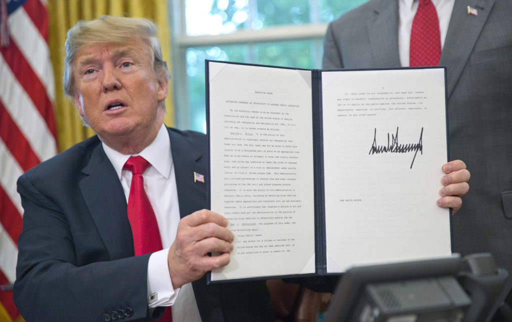 Trump holds up the executive order he signed to end family separations.