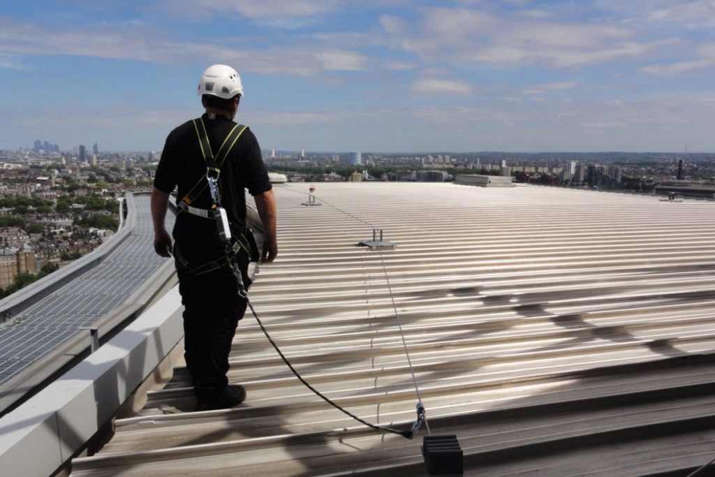 A construction worker on the roof showing proper OSHA standards.