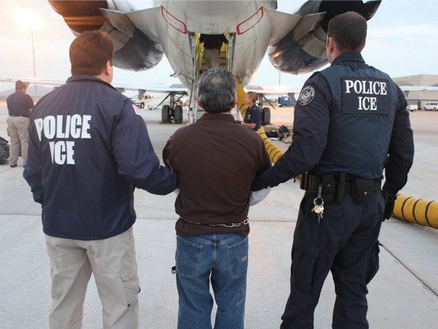 An immigrant is escorted to a plane to be deported by ICE