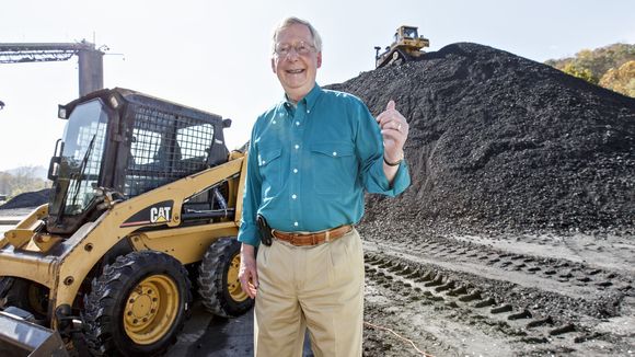 Mitch McConnell in front of a pile of coal.