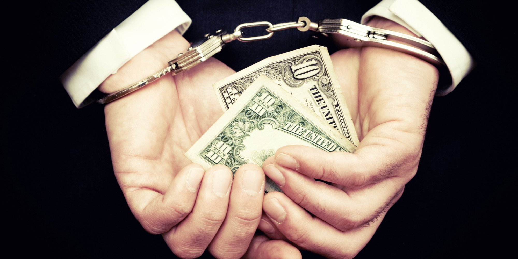 Businessman hands in cuffs holding money as Syracuse University finds fewer federal corruption charges under Trump