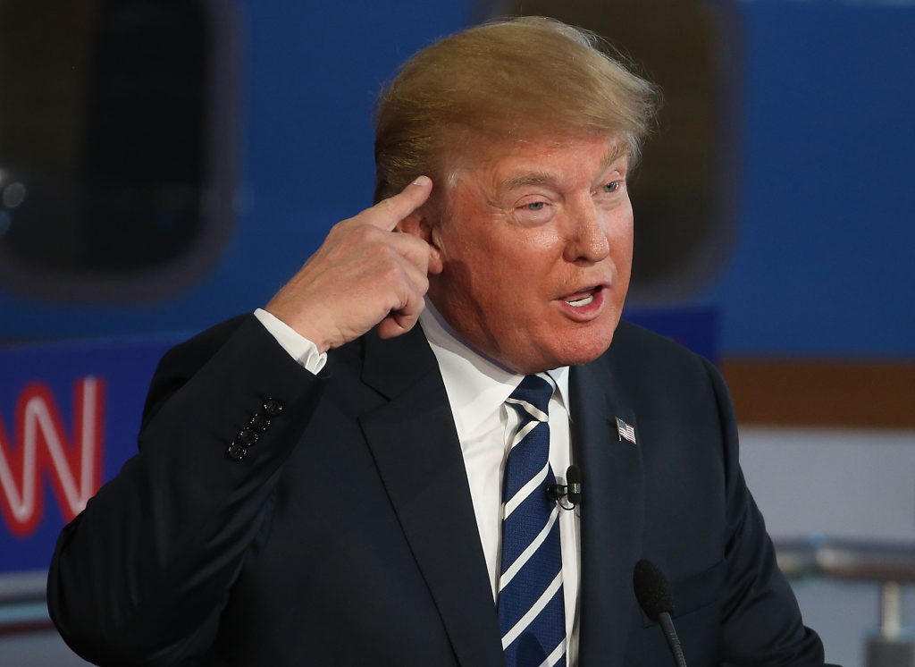 Donald Trump gestures with his hand to his head during a debate.