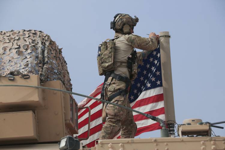 An American soldier mounts the U.S. flag on a vehicle near the town of Tel Tamr, north Syria.