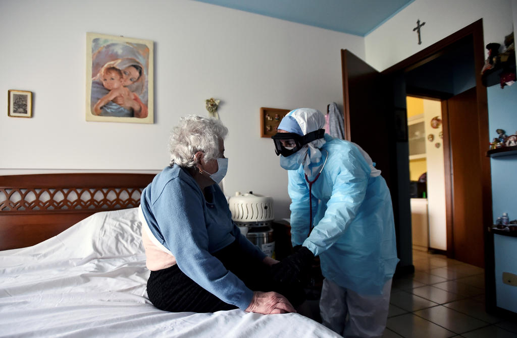 A doctor in protective suit visits a person suffering from the coronavirus disease (COVID-19) at her home in Bergamo, the epicentre of Italy's outbreak, April 16, 2020. REUTERS/Flavio Lo Scalzo