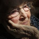 An Elderly Woman with her hand on her chin.
