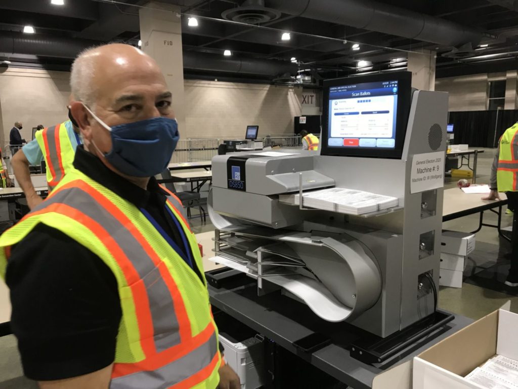 Dominion Voting Systems: A Poll Worker and a Voting Machine.