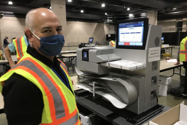 Dominion Voting Systems: A Poll Worker and a Voting Machine.