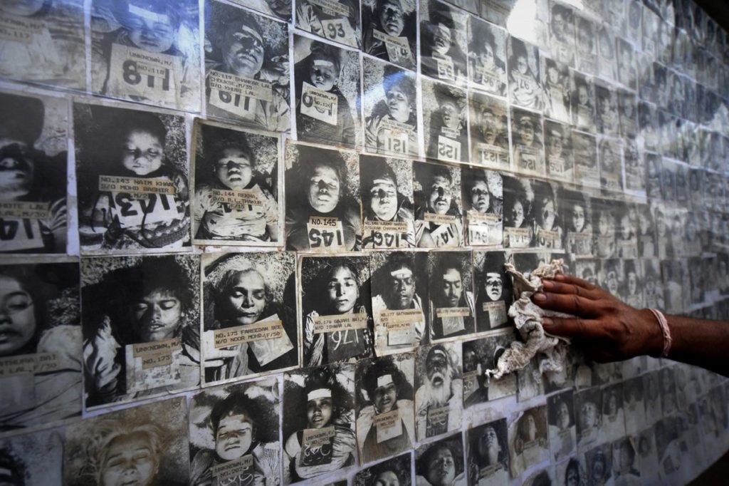 bhopal: A worker cleans dust as he displays a panel of photographs of some of the thousands of people who died in the 1984 Bhopal gas disaster at the forensic department of Gandhi Medical college in Bhopal on June 8, 2010. AP Photo/Prakash Hatvalne