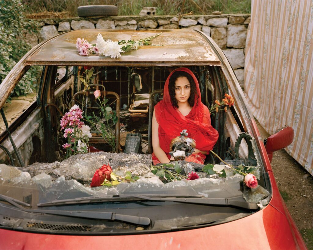 Activist Farah poses in her burnt car in Aabey, Lebanon in 2019.