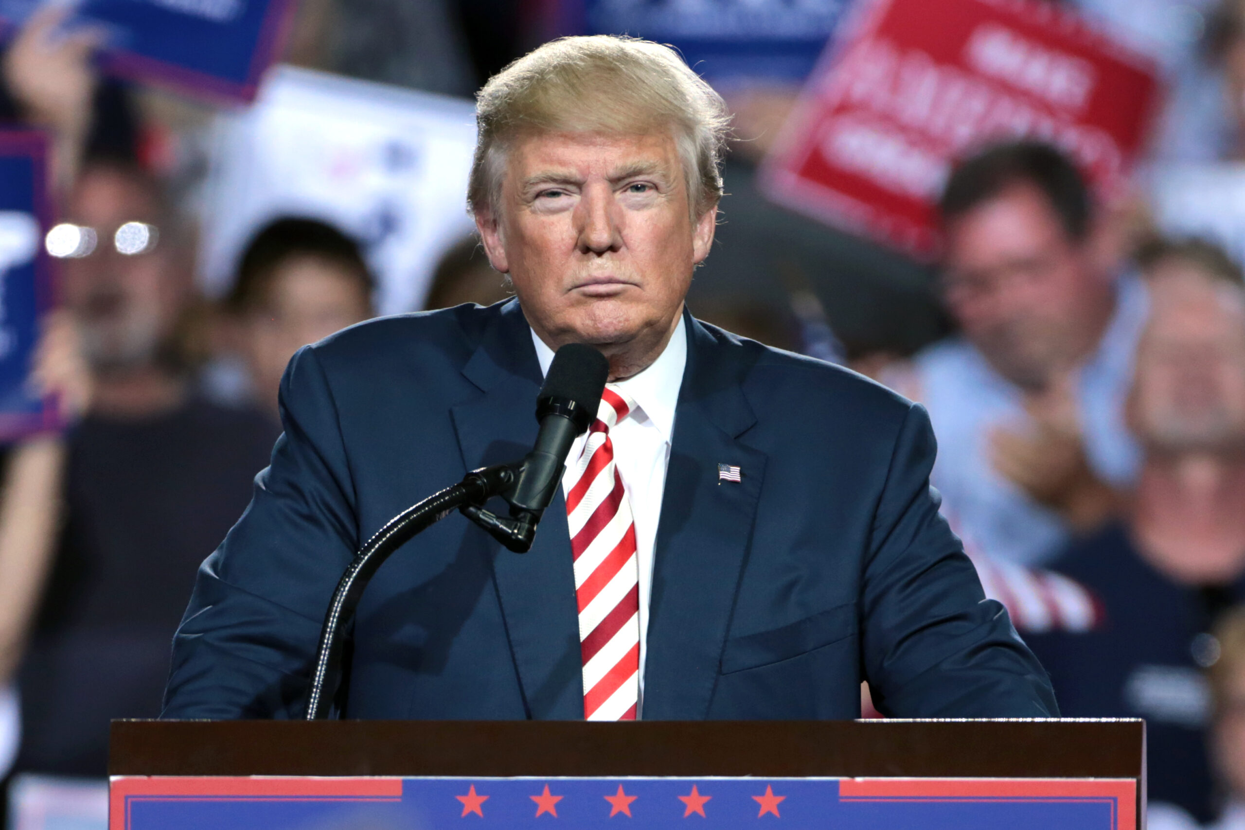 Donald Trump speaking at a podium during a rally.