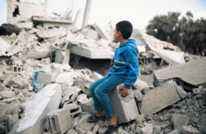 A child in Gaza sitting in rubble after an Israeli air strike.