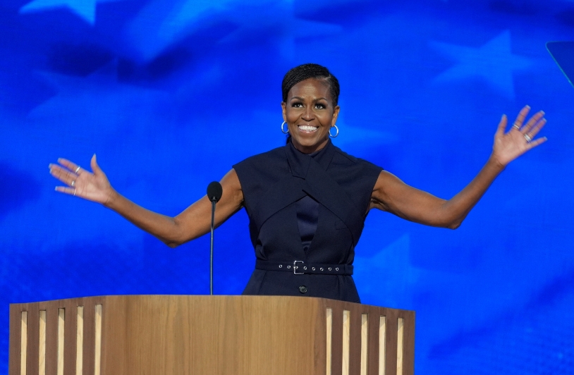 Michelle Obama speaking passionately with open arms at a campaign rally in Kalamazoo, Michigan, advocating for Kamala Harris and highlighting the importance of gender issues in the 2024 election.