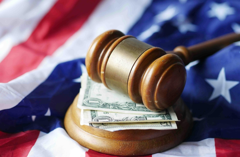Money under gavel on American flag.