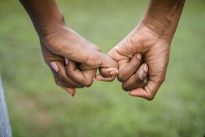 Two hands making a pinky promise, representing unity, trust, and mutual respect.