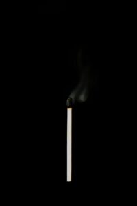 A burnt-out matchstick against a black background.