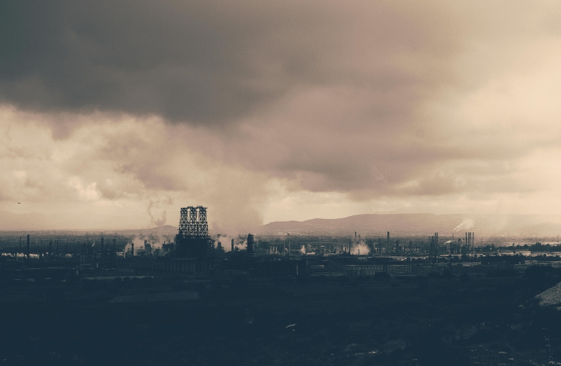 A heavily industrialized landscape with smokestacks releasing pollution into the air.