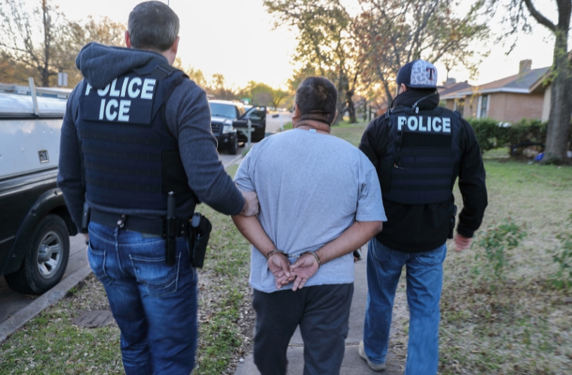 ICE officials handcuff suspect.