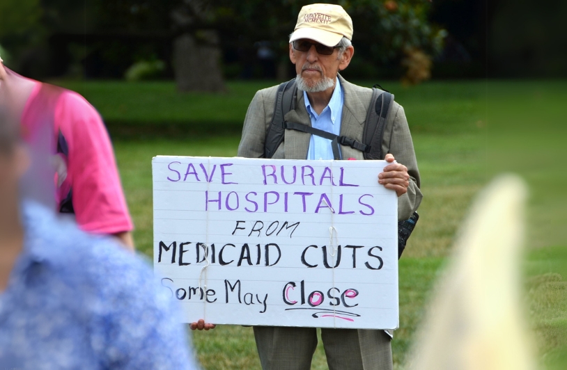 man holding sign about rural hospitals