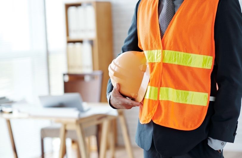 Unrecognizable male construction industry executive posing in safety vest, with hardhat.
