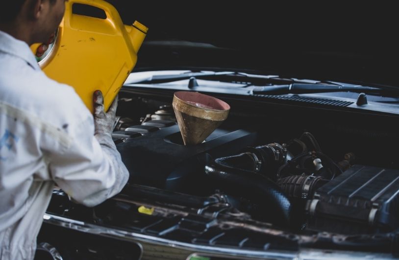 Close up auto mechanic hand pouring and replacing fresh oil into car engine at auto repair garage. Automobile maintenance and industry concept