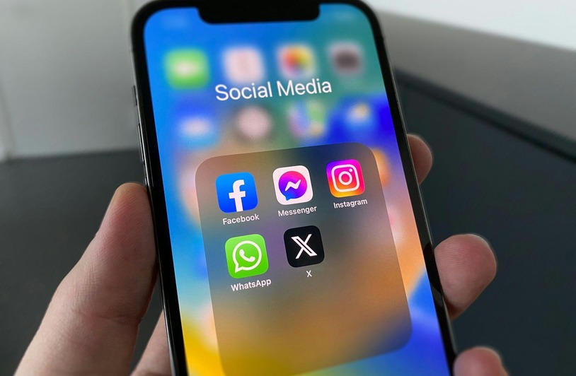 Person scrolling through social media on a smartphone at a desk