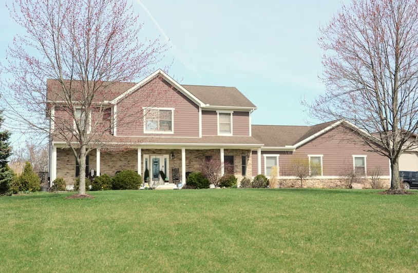A large suburban house with a well-maintained green lawn in front