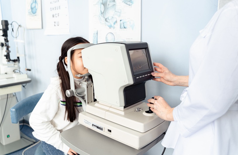 An optometrist examining a patient's eyes using a slit lamp in a clinical setting