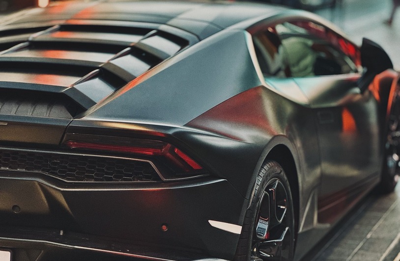 A sleek red Ferrari parked on a modern Dubai street with skyscrapers in the background