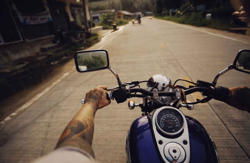 Motorcyclist riding along a scenic highway through open countryside on a sunny summer day.