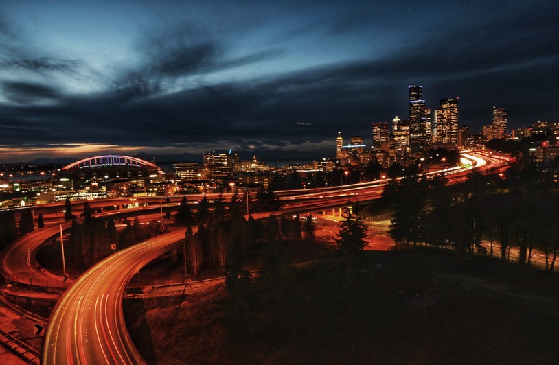 Multi-lane highway stretching through a green Pacific Northwest landscape under an overcast sky