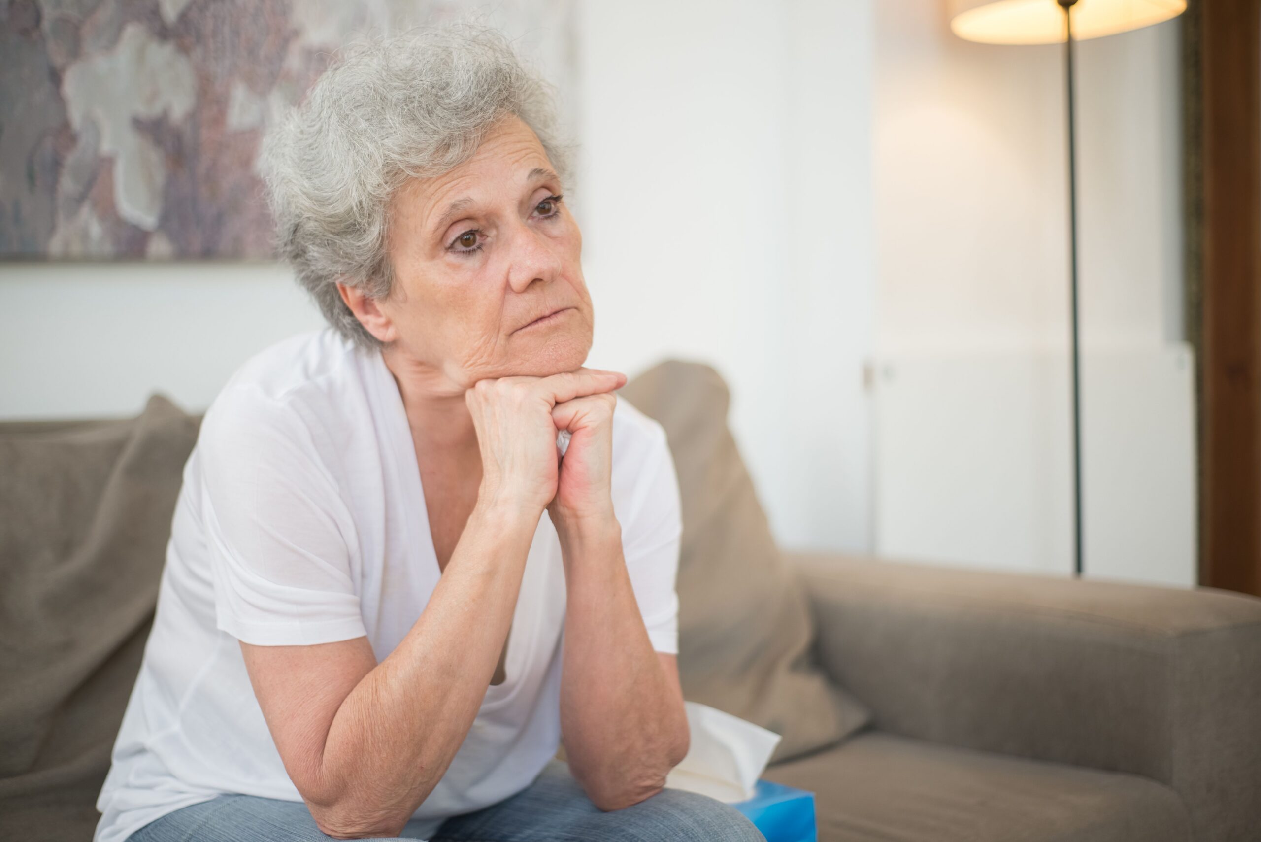 Elderly woman sitting on couch.