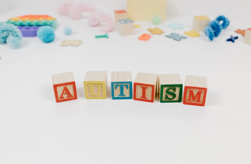 Choosing the Best Autism Therapy for Your Child Wooden blocks spelling autism surrounded by colorful toys on a white background.