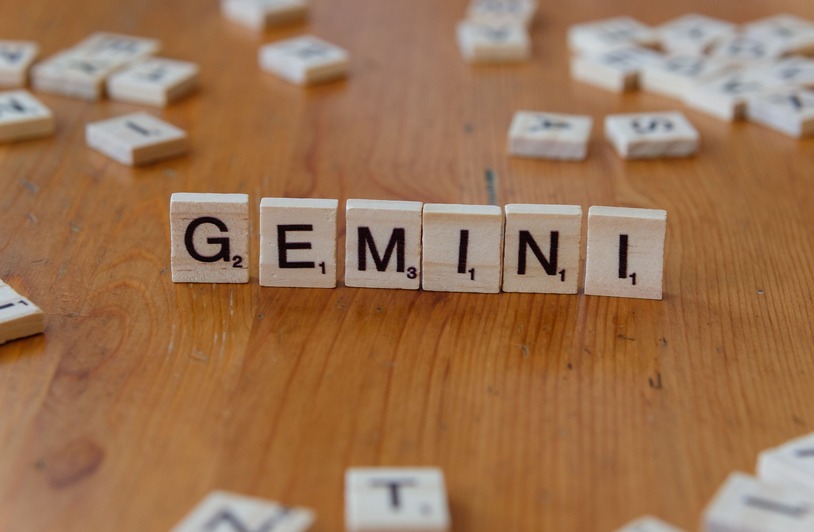 Gemini zodiac sign spelled with Scrabble tiles on a wooden table.