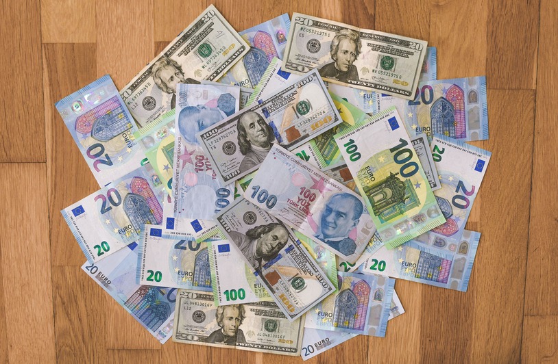 Foreign Investment Flows into Canada Signal Renewed Global Confidence A collection of US dollars, euros, and Turkish lira banknotes on a wooden surface.