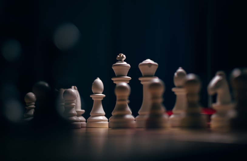 Close-up of chess pieces on a wooden board with dramatic lighting and selective focus.
