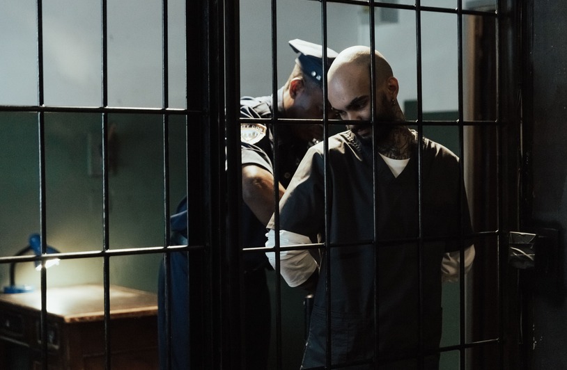 How Brett H. Knight Can Help You Stay Out of Jail A police officer handcuffing a male prisoner inside a cell with bars.