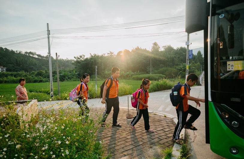 Children boarding a yellow school bus on a sunny morning