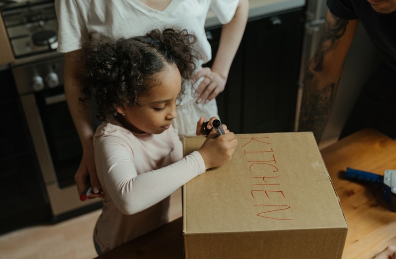 Modern Custody Models Moving Beyond Traditional Labels A mother and daughter label a cardboard box in their new kitchen, capturing the moving experience.
