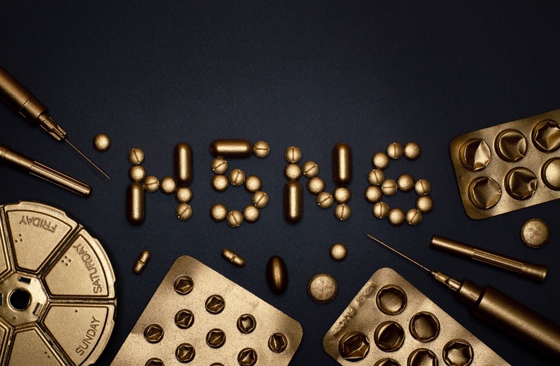 Golden pills and syringes arranged on a black background spelling H5N6.