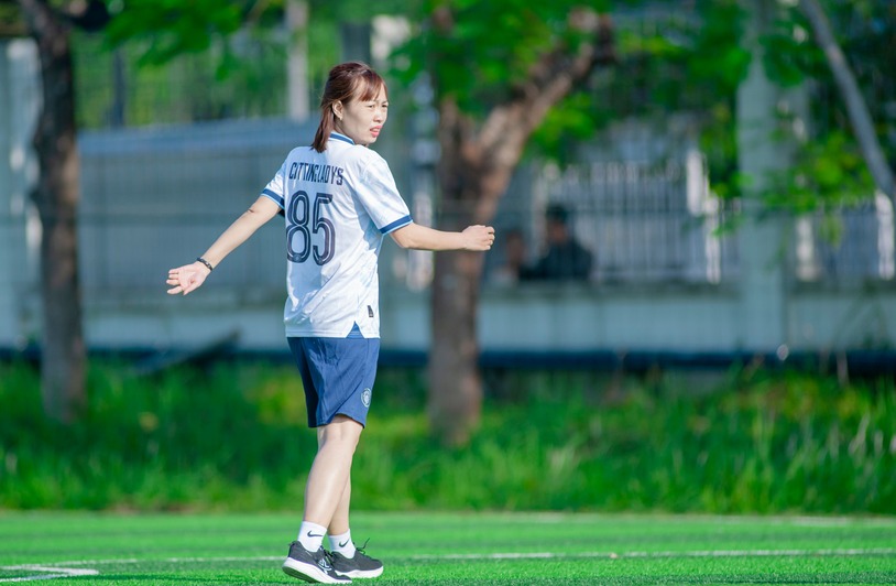 A young woman in sports attire playing soccer outdoors in Hà Nội, Việt Nam.
