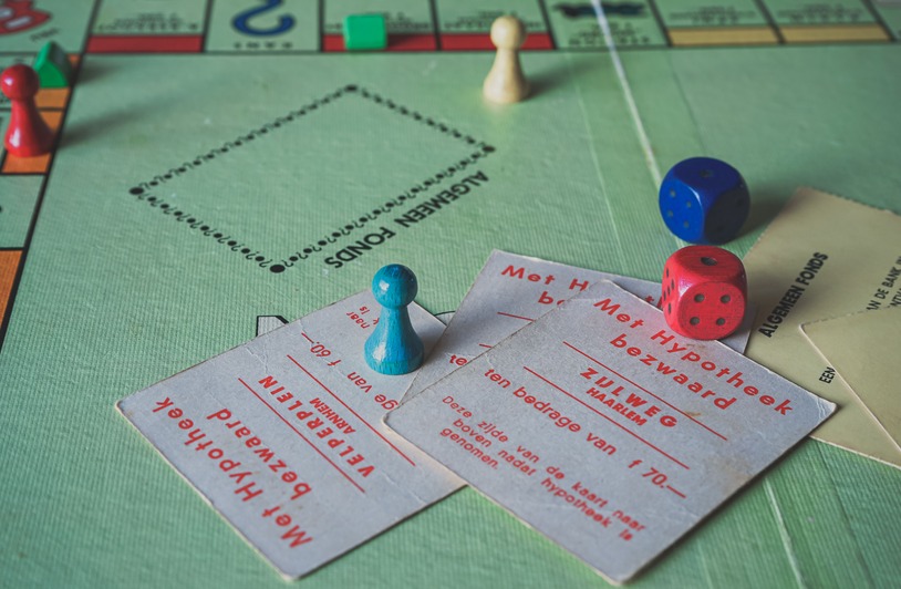 Politics as a Game of Chance: Why the Unpredictability of Reform Shapes Citizens’ Lives Close-up of vintage Monopoly game pieces and cards on a game board.