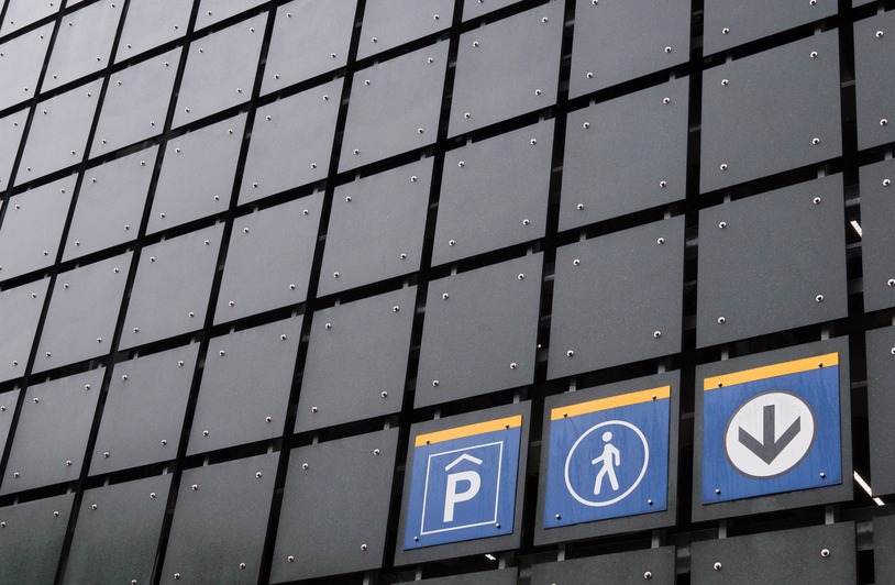Scaling Visual Language Without Building In-House Icon Sets View of modern building facade with parking and pedestrian signs illustrating urban design.