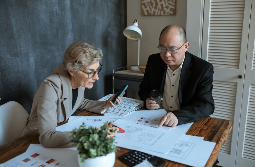Diverse team of professionals working on project plans at a desk. Collaborative business environment.