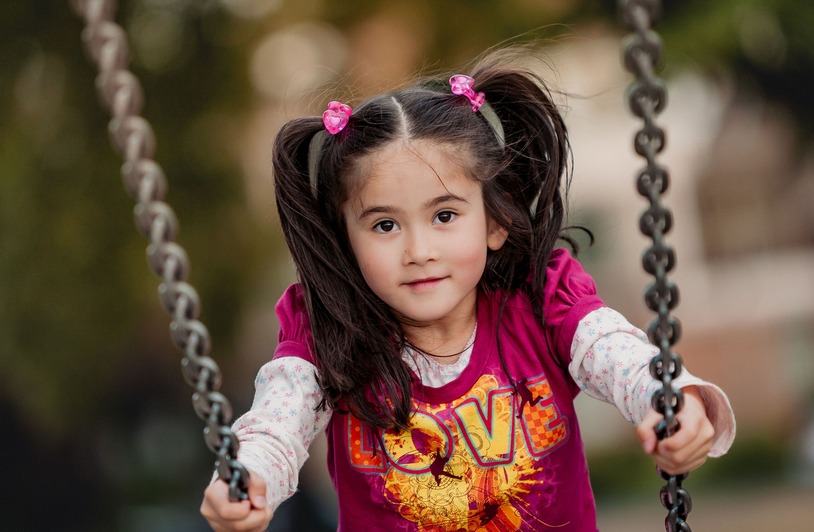 The Backyard Features That Make Kids Want to Stay Outside Longer A young girl enjoying a swing ride in a Canadian park, capturing the joy of childhood outdoors.