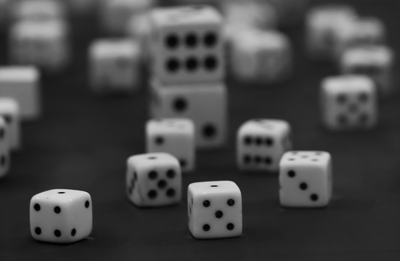 The Balance Between Chance and Calculation Black and white photo of scattered dice, focusing on one die in sharp detail.