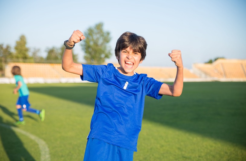 Joyful boy celebrating a soccer win outdoors in Portugal.